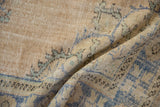 Worn hand-knotted pile of a vintage Oushak rug with soft folds in beige, pale blue, and seafoam green.