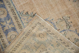 Folded corner of a vintage Oushak carpet showing the hand-knotted weave and distressed low pile.
