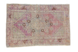 Distressed Turkish Oushak rug with a faded purple and seafoam green medallion over a worn ivory field.