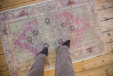 A person's view standing on a distressed Oushak rug showing its scale and texture.