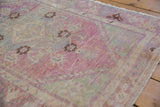 Heavily distressed texture on a vintage Oushak rug with time-softened purple and green hues.