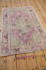 Angled perspective of a vintage Oushak rug showcasing its distressed texture and faded purple palette.