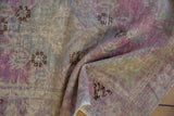 Softly draped vintage Oushak rug showing low pile, patina, and muted purple and slate tones.
