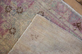 Folded corner of a distressed Oushak rug shows its hand-knotted foundation and secured side selvage.