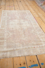 Vintage distressed Oushak rug texture, showing low pile, muted mauve tones, and visible foundation.