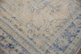 Distressed Oushak rug detail showing worn pile, visible foundation, faded cream and blue vinery.