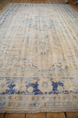 Vintage distressed Oushak rug showing worn cream and pale blue vinery patterns.