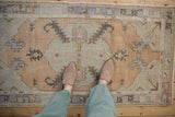 Vintage distressed Oushak rug texture with muted dusty gold, pale blue, and grey patterns.