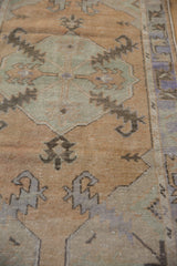 Distressed Oushak rug detail with serrated leaf motif, sandalwood, and faded grey tones.