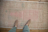 View looking down at the soft texture of a distressed vintage Oushak rug with pink and sand tones.