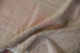 Hand-knotted texture and short pile of a distressed rug in pale pink and sand tones.