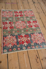 Distressed Oushak rug featuring rose, red quatrefoil medallions on dusty blue and slate green.