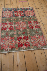 Distressed vintage Oushak rug with worn slate green field and rose, red, ivory quatrefoil motifs.