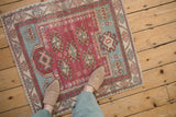 Small square vintage Oushak rug in raspberry and dusty blue, seen from above to show its scale.