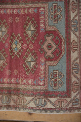 Close-up on the corner of a distressed Oushak rug with a dusty blue spandrel and geometric borders.