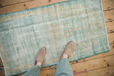 Textured pile of a distressed vintage Oushak rug in faded mint green and beige.