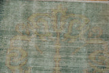 Textural close-up of distressed vintage Oushak rug, showing worn mint green and beige pile.