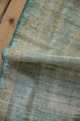 Distressed vintage Oushak rug corner showing worn pile, faded mint, and beige tones.