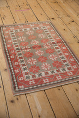 Decorative distressed Oushak rug displaying alternating pale cherry red and taupe geometric motifs.