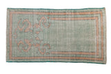 A distressed vintage Oushak rug in pale mint green with a dusty gold scrolling prayer design.