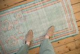Time-worn texture of a distressed Oushak rug in pale mint green and dusty gold.