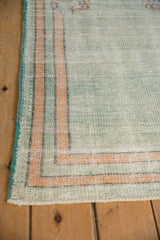 Visible knot heads and striped border on the corner of a distressed Oushak rug.