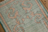 Low-pile texture of scrolling dusty gold vines on a distressed mint green Oushak rug.