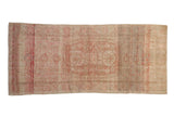Distressed Oushak runner with faded oblong medallion and floral design in blush red and neutral tones.