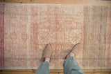 Textural distressed Oushak runner with faded ivory, sand, and rose floral medallion pattern.