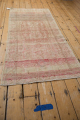 Distressed vintage Oushak runner with faded red meandering vine border and floral motifs.