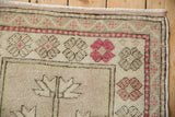 Oushak rug corner detail, featuring raspberry serrated flowers, checkered border, and distressed pile.
