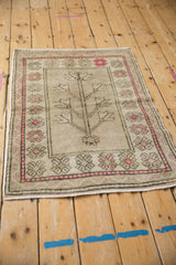 Distressed Oushak rug's tree of life motif with sunned, muted tones and even pile wear.