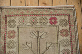 Upper corner of a distressed Oushak rug, showing tree of life base and faded raspberry flowers.