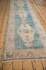Distressed Oushak runner detail: ivory scalloped medallion with pinwheel floral motifs on dusty aqua teal.