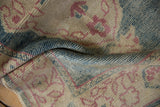 Distressed wool pile texture in dusty aqua, ivory, and faded burgundy on a vintage Oushak rug.