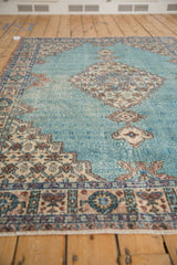 Close-up: Distressed vintage Sparta rug field with powder blue, ivory stepped medallion, germinating vine motifs.
