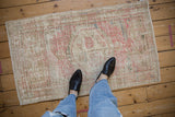 The mostly even wear and soft texture of a vintage Oushak rug, seen from a standing view.