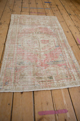 Angled view of the distressed Turkish rug showing its low, worn pile and soft pink and sand colors.