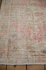 Distressed texture of a hand-knotted rug with foundation visible through the pink and sand pile.