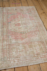 Angled view of a distressed Oushak rug showing worn texture and exposed foundation.