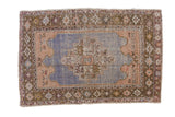 A vintage distressed Oushak rug with a stepped center medallion in dusty blue, sandalwood, and olive green.