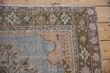 Stylized olive green border and sandalwood corner detail on a distressed hand-knotted Oushak rug.