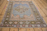 A vintage distressed Oushak rug's faded palette and worn, low pile seen from an angle.