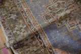 A distressed Oushak rug folded, revealing its low, worn pile and hand-knotted foundation.