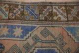 Distressed geometric border of a vintage Melas rug in faded blue, terracotta, and brown.