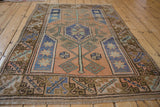 Distressed Melas rug corner with geometric brown, blue, terracotta border and fringe.