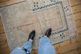Distressed Turkish Melas rug corner, with cobalt blue geometric border and dusty rose starburst motifs.