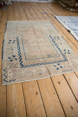 Distressed Melas rug corner with cobalt geometric pinwheel design and muted rose.