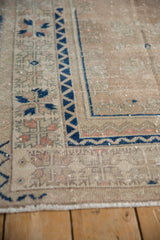 Distressed vintage Melas rug corner with geometric cobalt blue border and dusty rose blossoms.