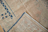 Folded corner of distressed Melas rug showing worn light pile, visible foundation, and blue selvage.